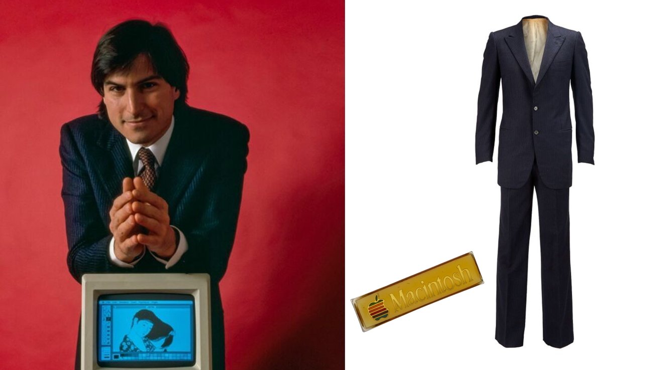 Steve Jobs in blue pin-stripe suit with clasped hands, vintage computer displaying artwork, suit on display with a Macintosh pin.