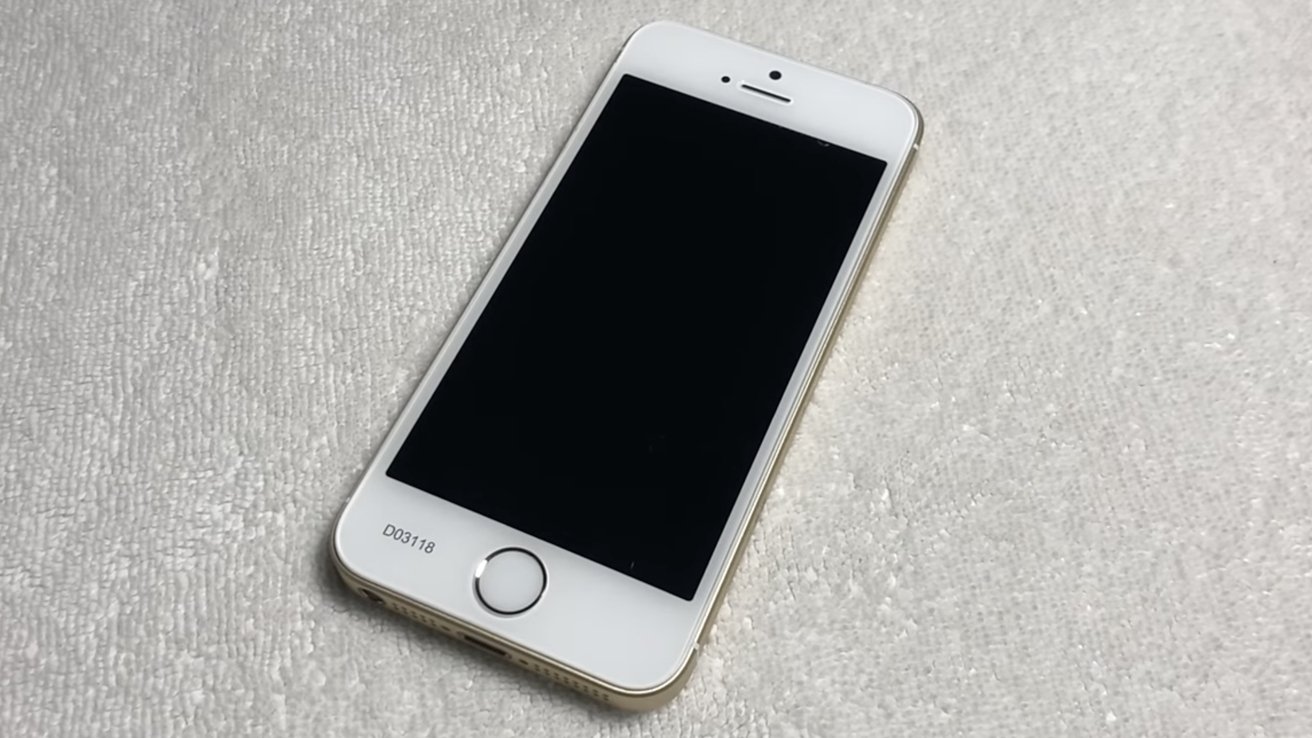 A white smartphone with a black screen rests on a textured, light-colored surface.