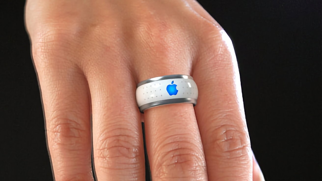 Hand wearing a metallic ring with a blue, glowing apple logo and a dotted pattern on a black background.