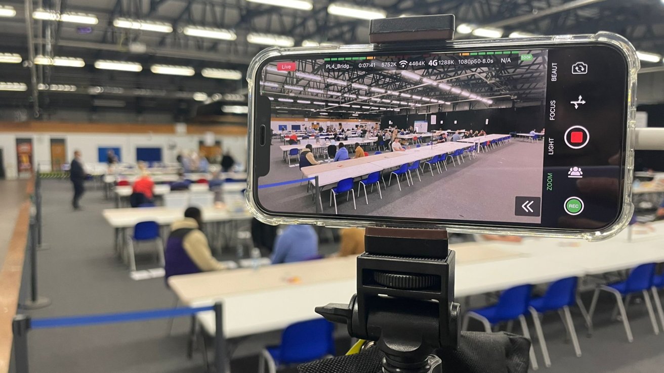 An iPhone 12 on a tripod pointed at a voting area