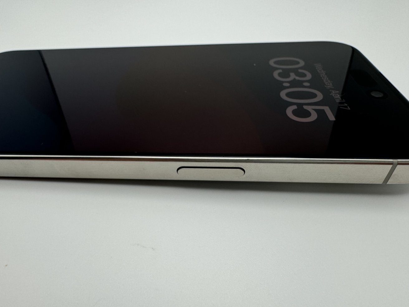 Smartphone lying flat on a white surface with screen showing the time 03:05.