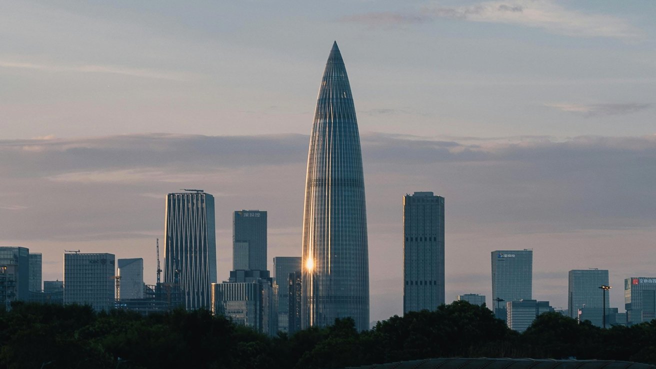 City skyline with tall buildings at dusk, one standout building shaped like a tapered cylinder, with a sun reflection.