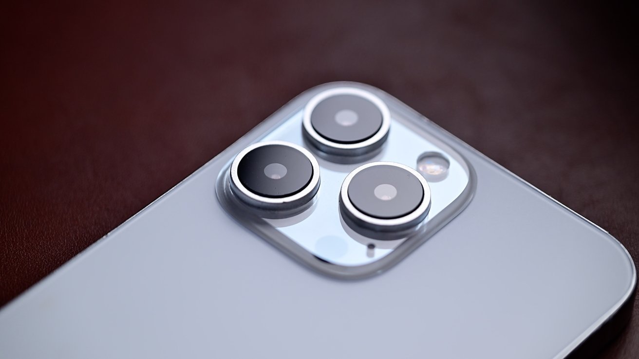 Close-up view of a modern smartphone's triple camera system with metallic edges on a reflective surface.