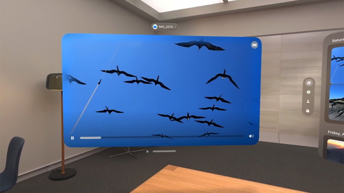 Video displaying birds flying on a large screen in a modern room with a lamp, chair, and wooden furniture.