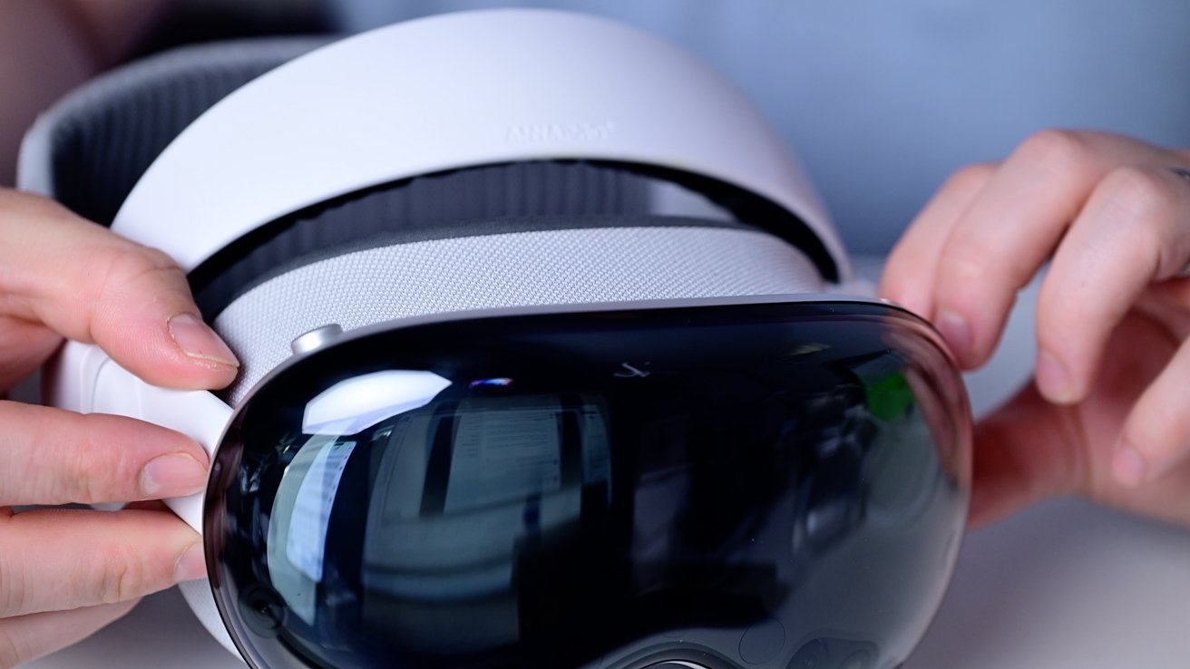 Hands holding a white virtual reality headset with a dark reflective front visor.