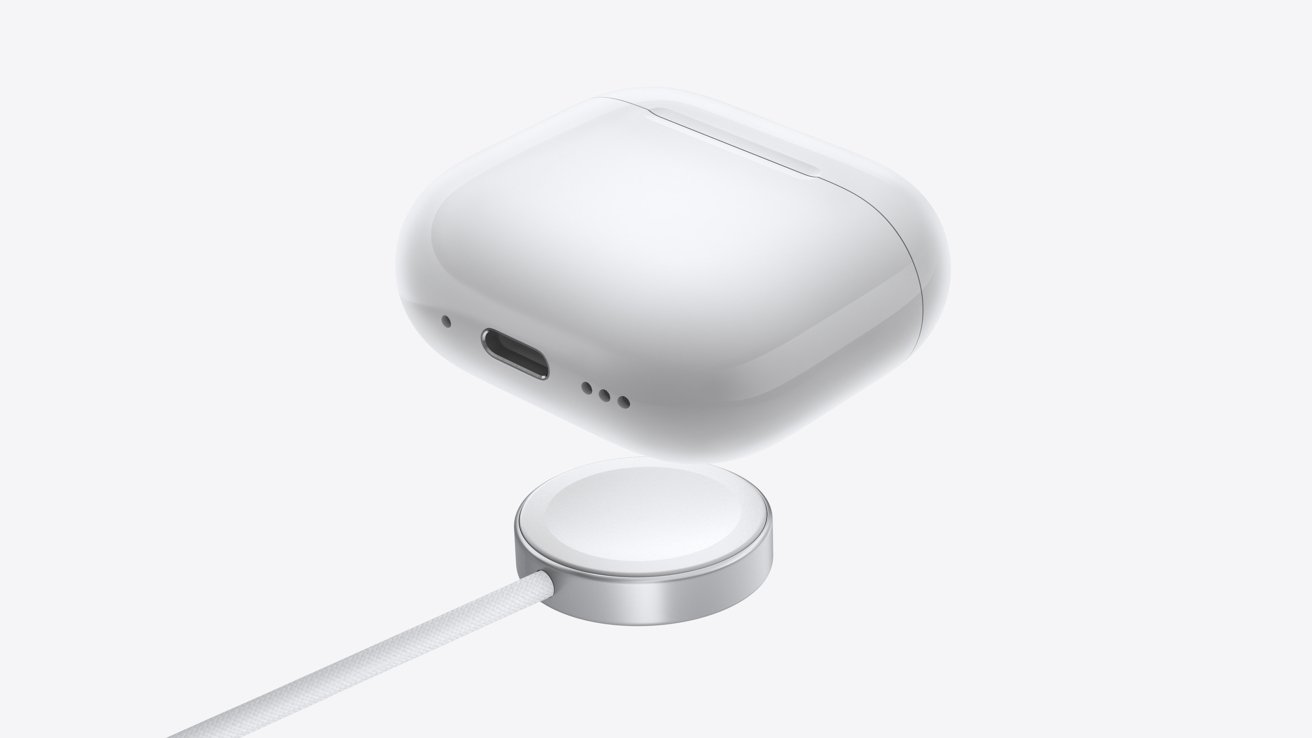 White wireless earbuds case floating above a circular charging stand with a cable connected, on a white background.