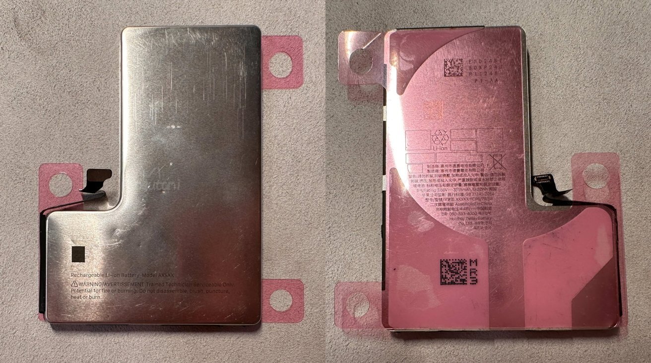 Silver and pink rectangular metal objects with attached black connectors, placed on a soft, textured grey surface. Some text and QR codes are visible on the pink sides.