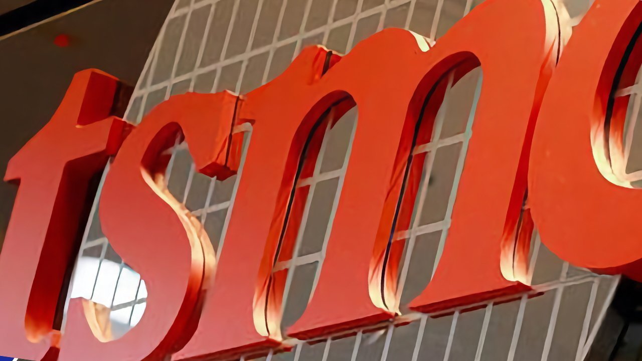 Large red letters 'tsmc' on a reflective building with a grid-like window pattern in the background.