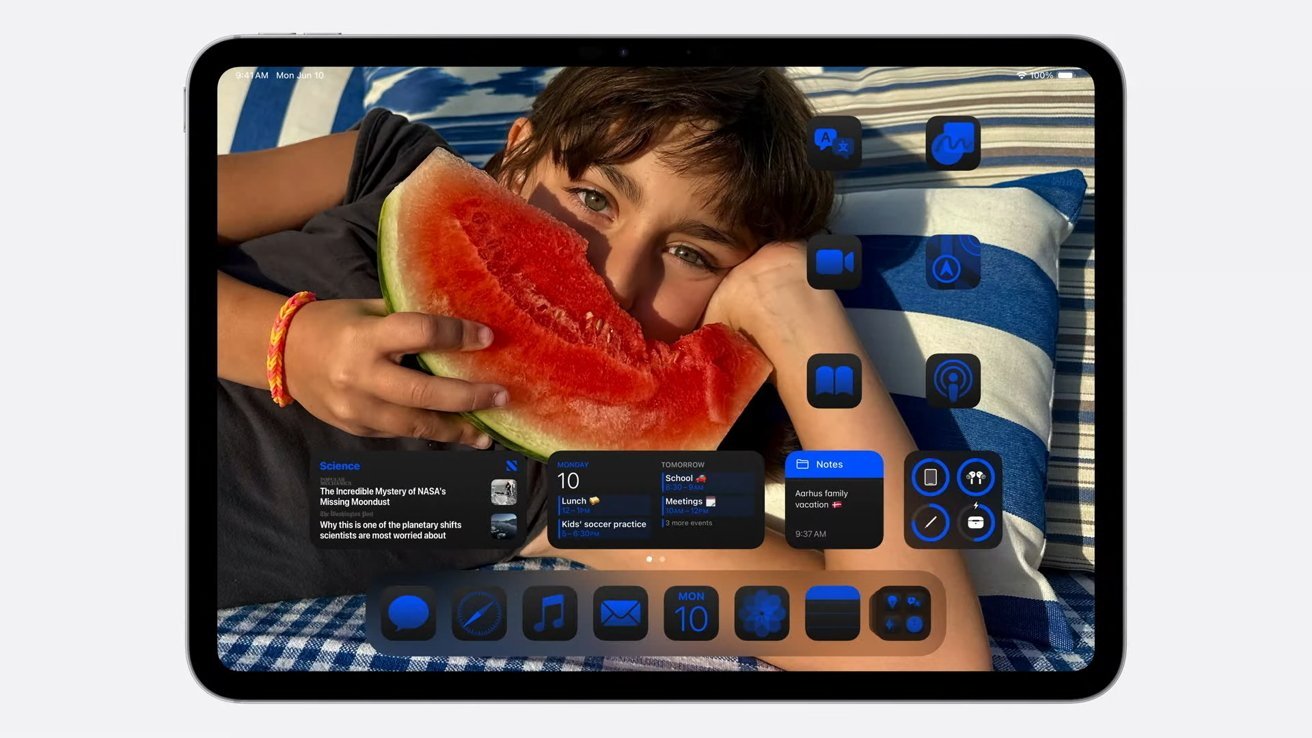 A child holding a slice of watermelon, with iPad home screen icons and widgets overlayed, lying on a striped cushion outdoors.