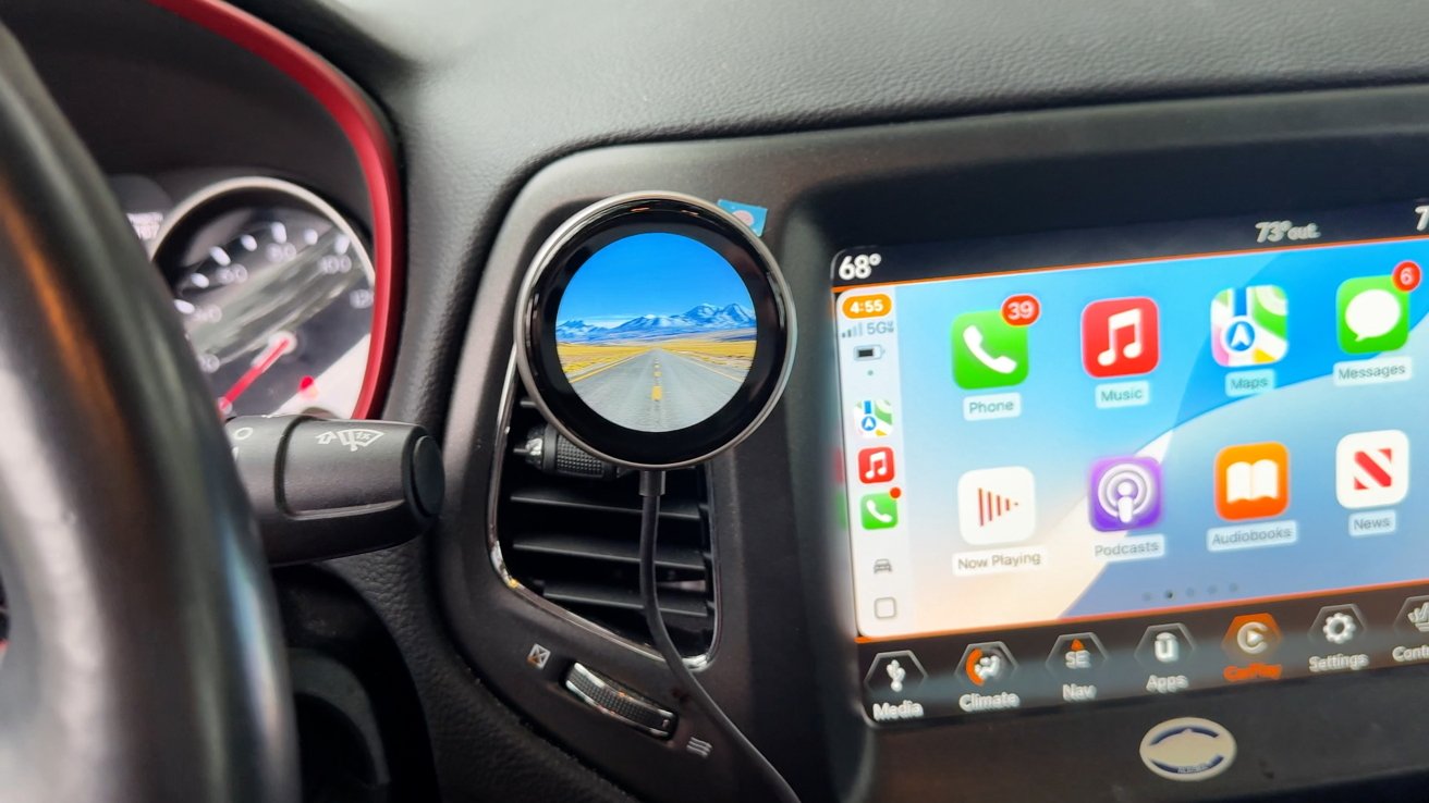 Car dashboard with digital display with various application icons, GPS map and temperature information; a phone holder is attached to the air vent.