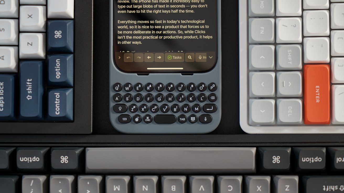 Multiple keyboards with various color keys surround a smartphone with a tactile keyboard attachment. The smartphone screen displays a text document.