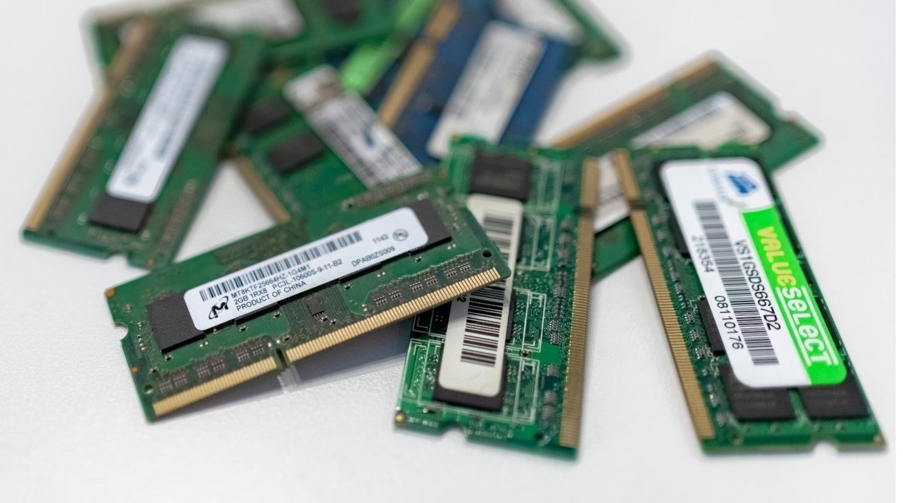 Several green RAM memory sticks with labels, including barcodes and specifications, are scattered on a white surface.