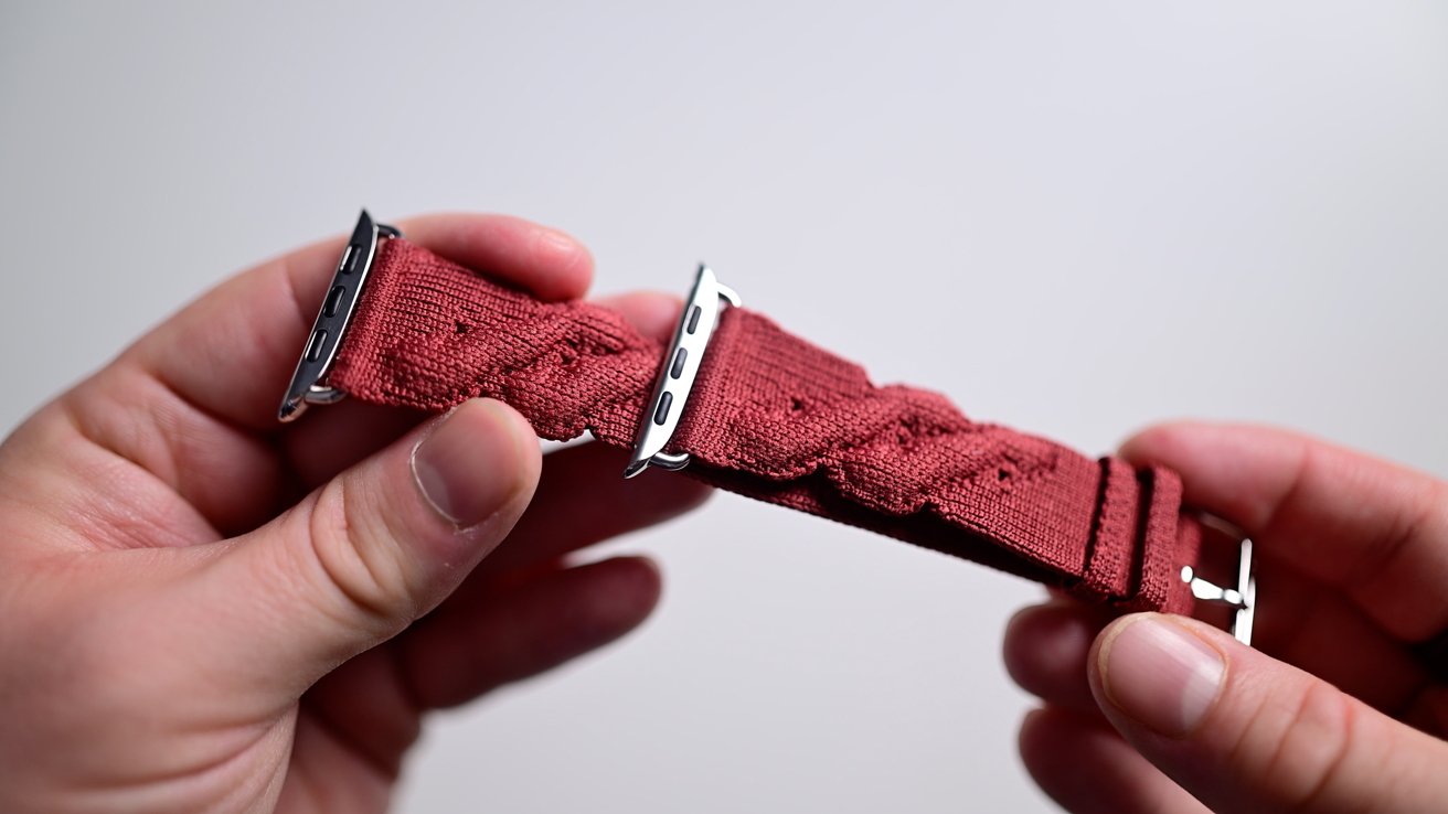 Holding the dark red woven Torsade Apple Watch band