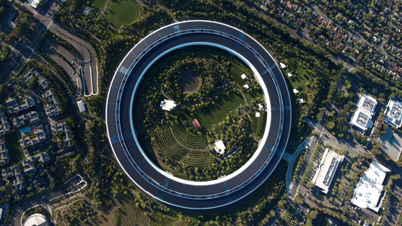 Aerial view of a large, circular building surrounded by greenery and smaller urban structures.