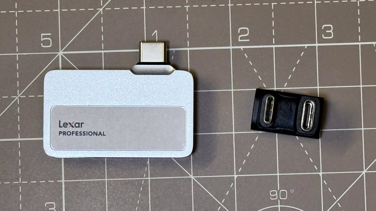 Silver Lexar Professional card reader and black USB-C adapter. It is on a gray cutting mat with grid lines.