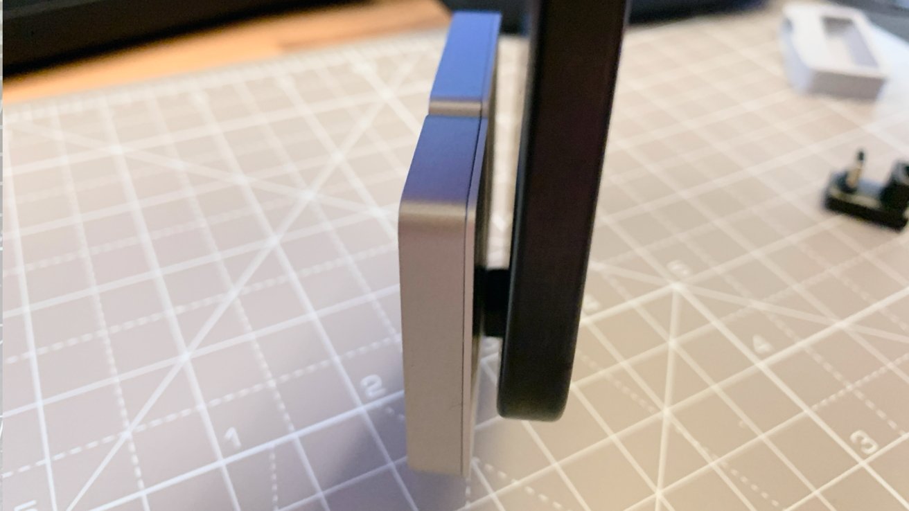 Side view of a computer monitor on a stand next to a checkered cutting mat on a desk.