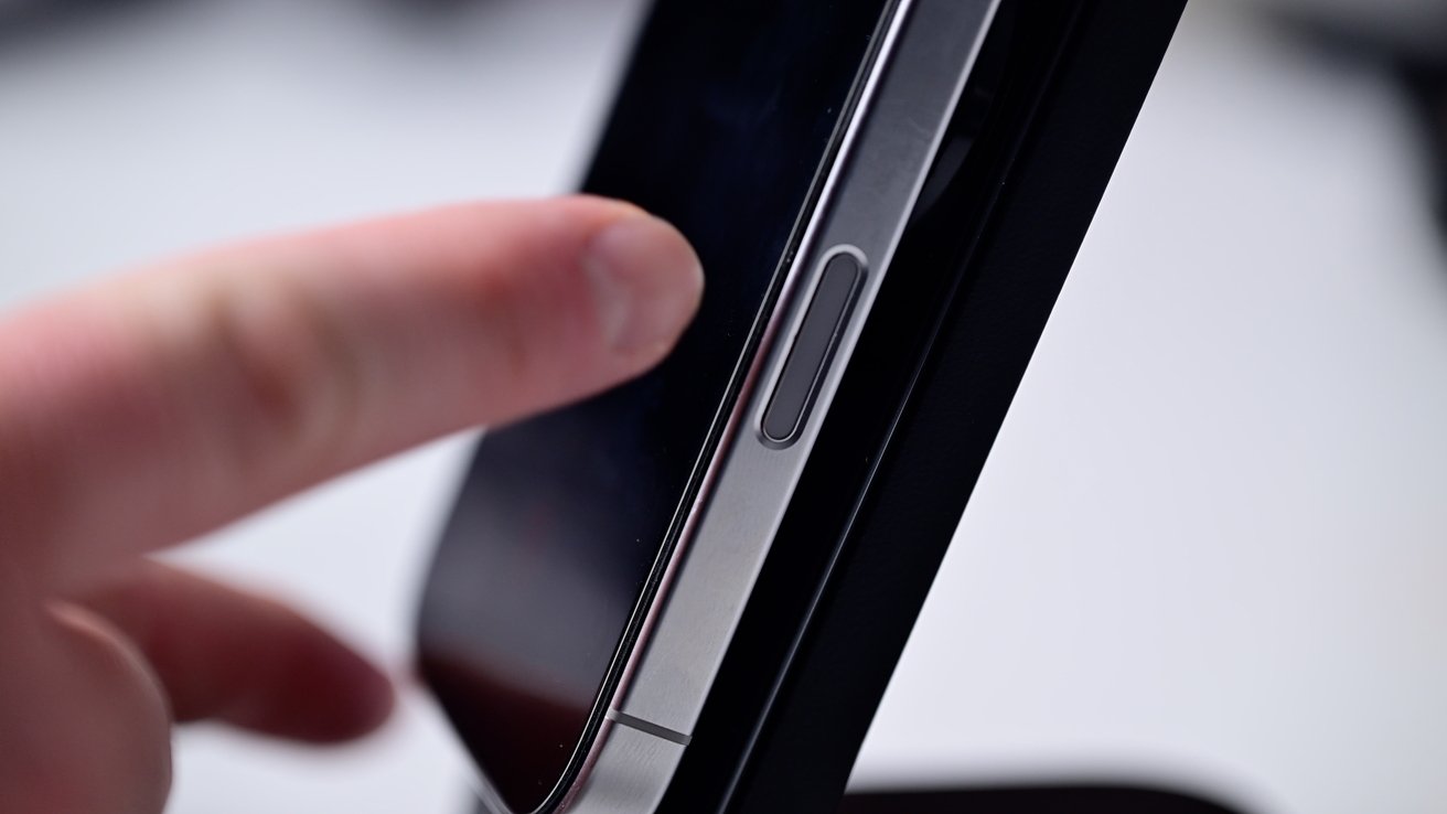 Finger touching the screen of a smartphone with focus on the device's side button.