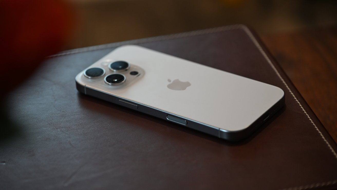 A smartphone with three camera lenses on a brown leather surface.