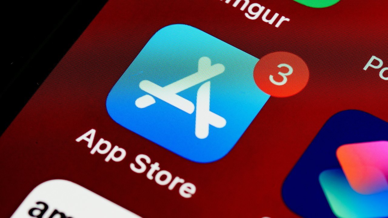 Close-up of App Store icon showing three notifications, displayed on a smartphone screen with a red background.