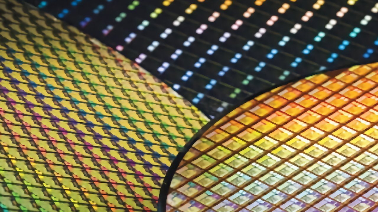 Colorful grid pattern on a silicon wafer, displaying iridescent, rainbow-like reflections with repetitive square shapes, creating a shiny, geometric appearance.