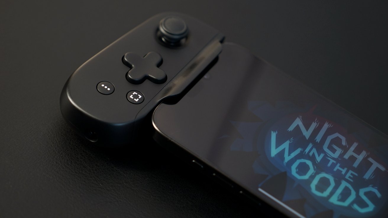 Black gaming controller attached to a smartphone displaying 'Night in the Woods' title screen on a dark surface.