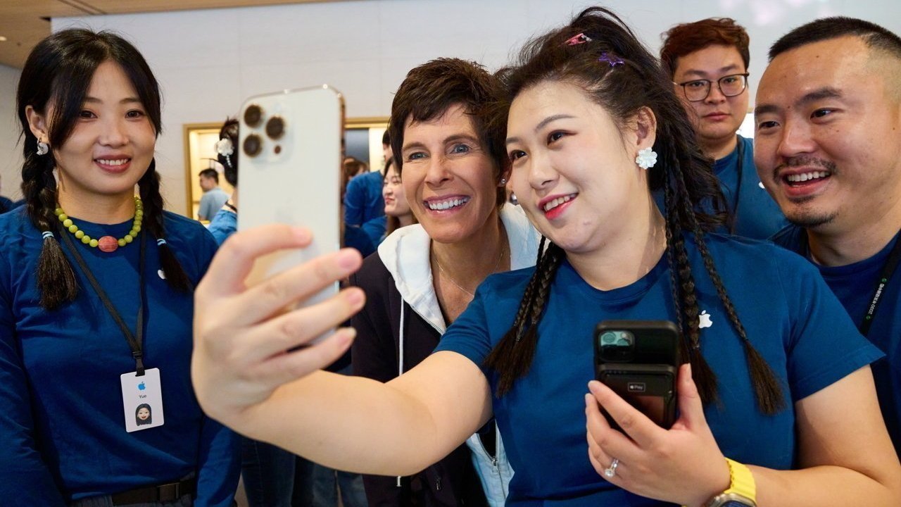 A group of people in matching shirts taking a selfie, smiling and gathered closely together.