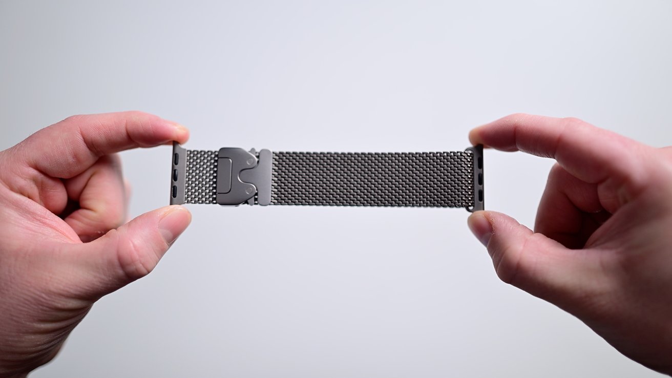 Two hands have a Metal Watch band with a network design against a common background.