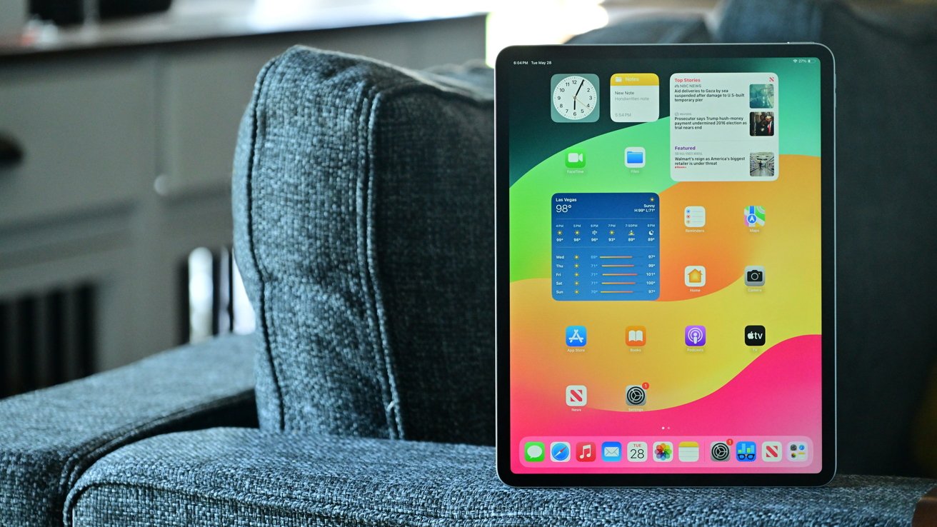 An iPad Air displaying colorful widgets and apps on a sofa with a gray textured fabric.