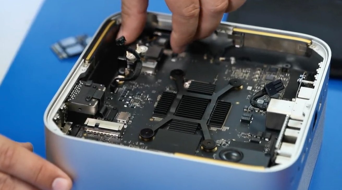 A person's hand adjusting components inside an open computer case, revealing a motherboard, ports, and other electronic parts.