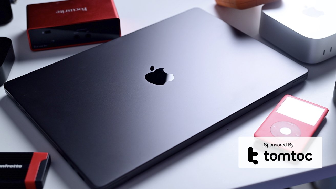 A MacBook Pro sitting on a desk surrounded by accessories