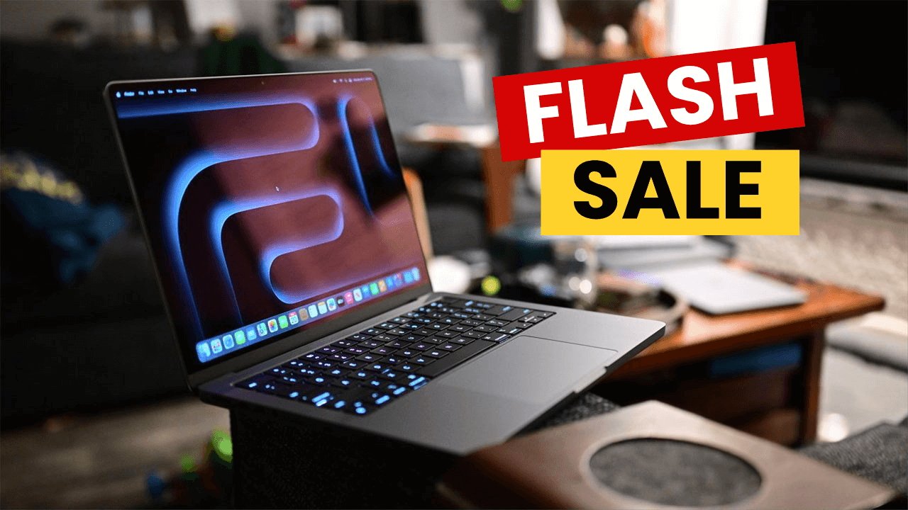 Open MacBook Pro on a table showing a colorful screen, with a bold flash sale banner in red and yellow nearby.