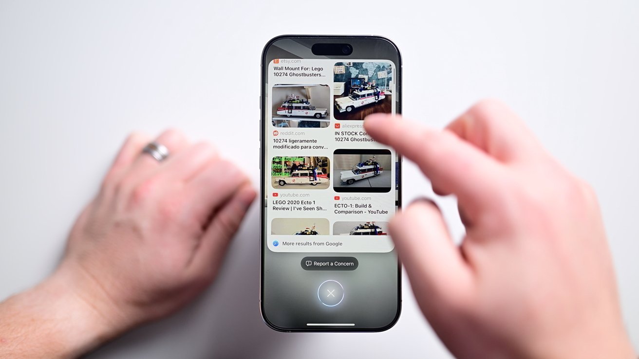 Two hands interact with a smartphone displaying search results for a LEGO Ghostbusters vehicle.