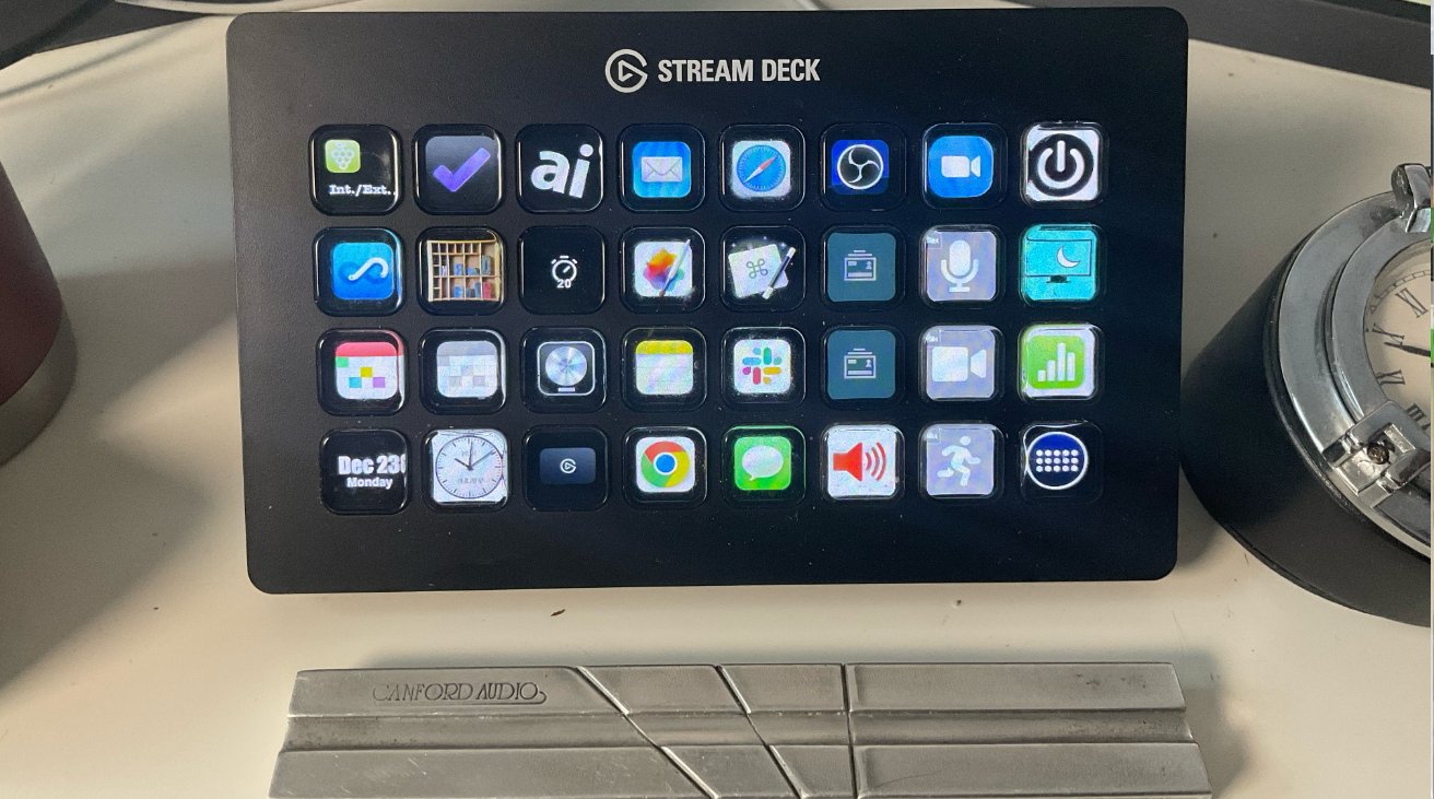 Stream deck with illuminated buttons, each displaying different app icons, on a desk beside a vintage clock and metal accessory.