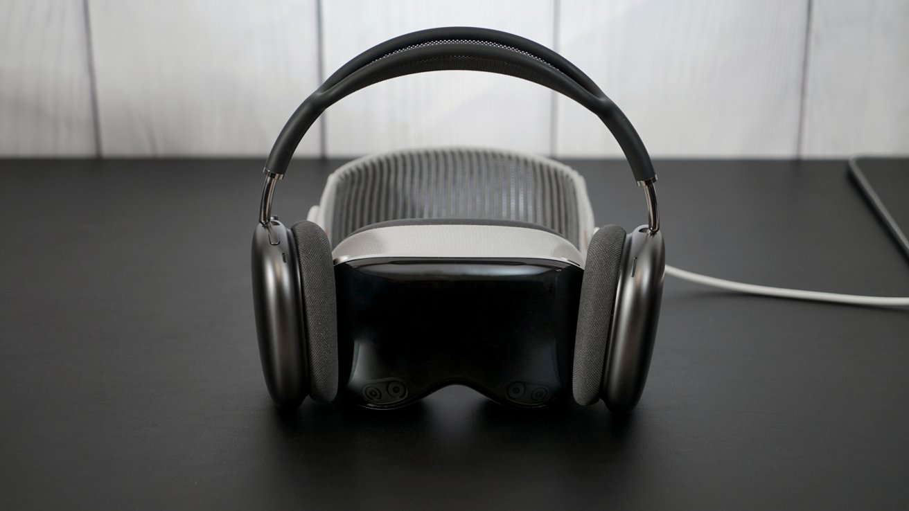 Headphones resting on a black surface, with a virtual reality headset positioned behind them.