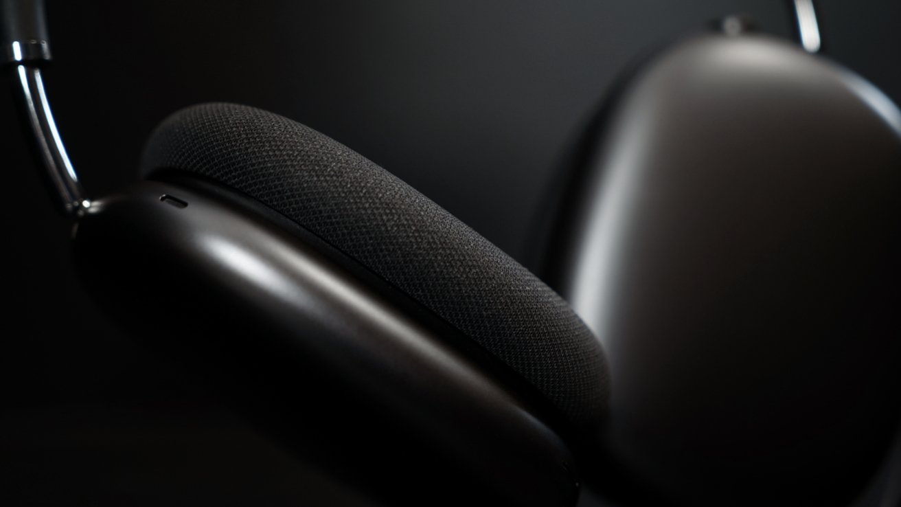 Close-up view of sleek, modern over-ear headphones with dark cushioned ear pads against a black background.