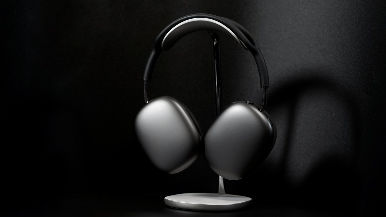 Sleek, modern over-ear headphones in dark gray, resting on a stand against a black background.