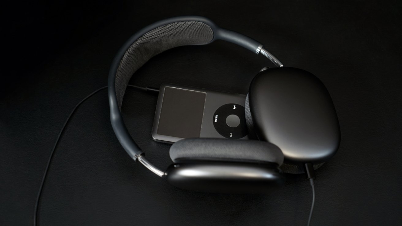 Headphones and a portable music player with a circular control pad, both in black, placed on a dark surface.