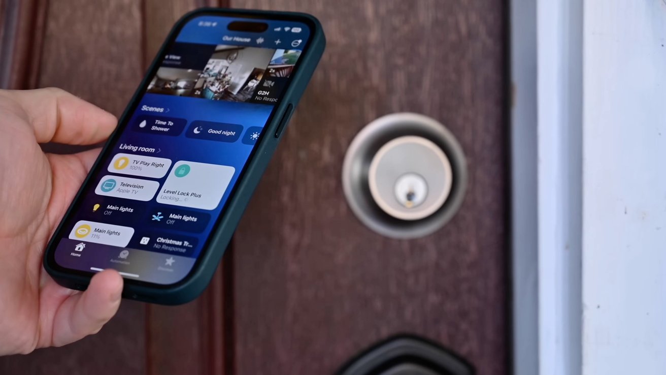 Hand holds smartphone displaying smart home app near a door lock.