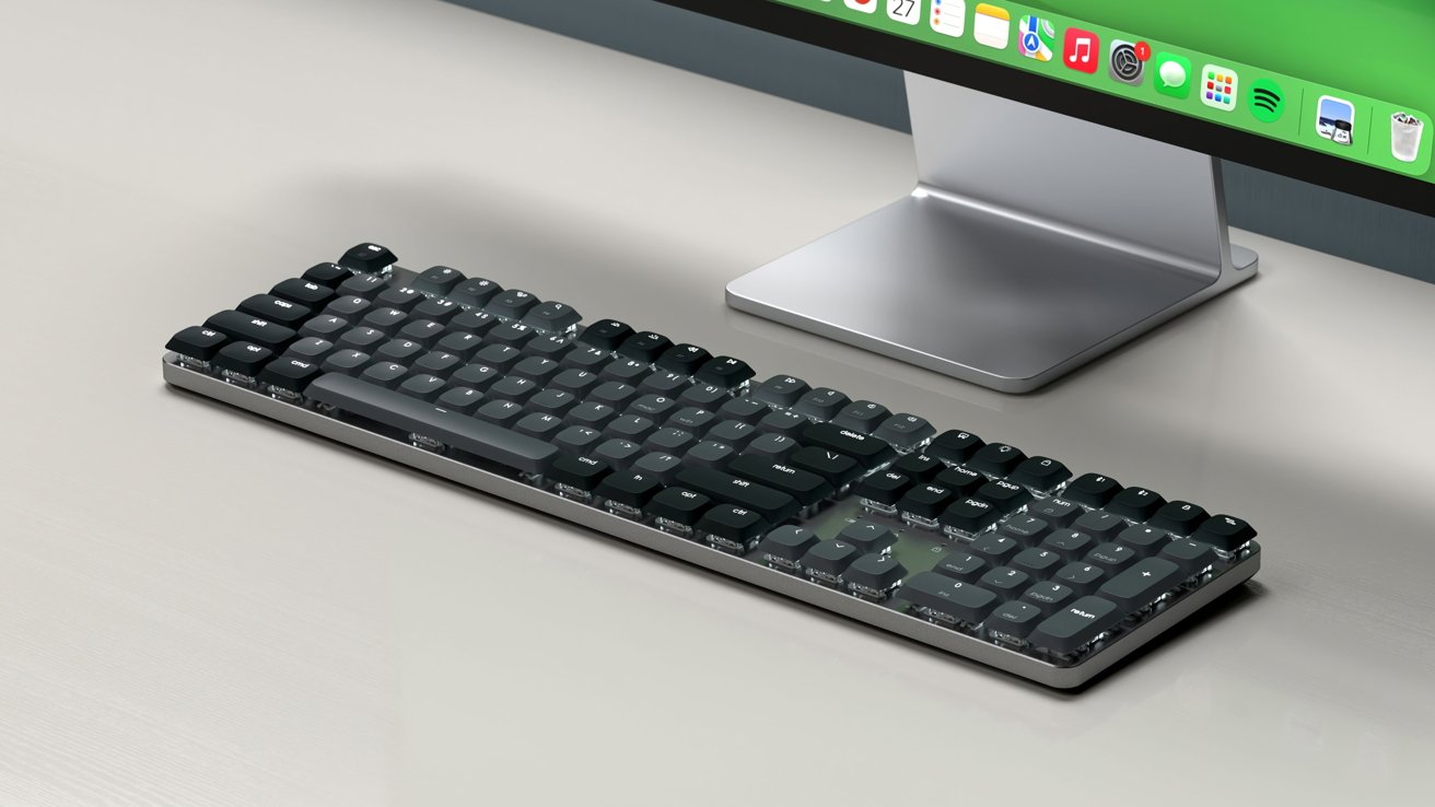 A sleek black mechanical keyboard on a desk in front of a modern computer monitor displaying a green desktop screen.