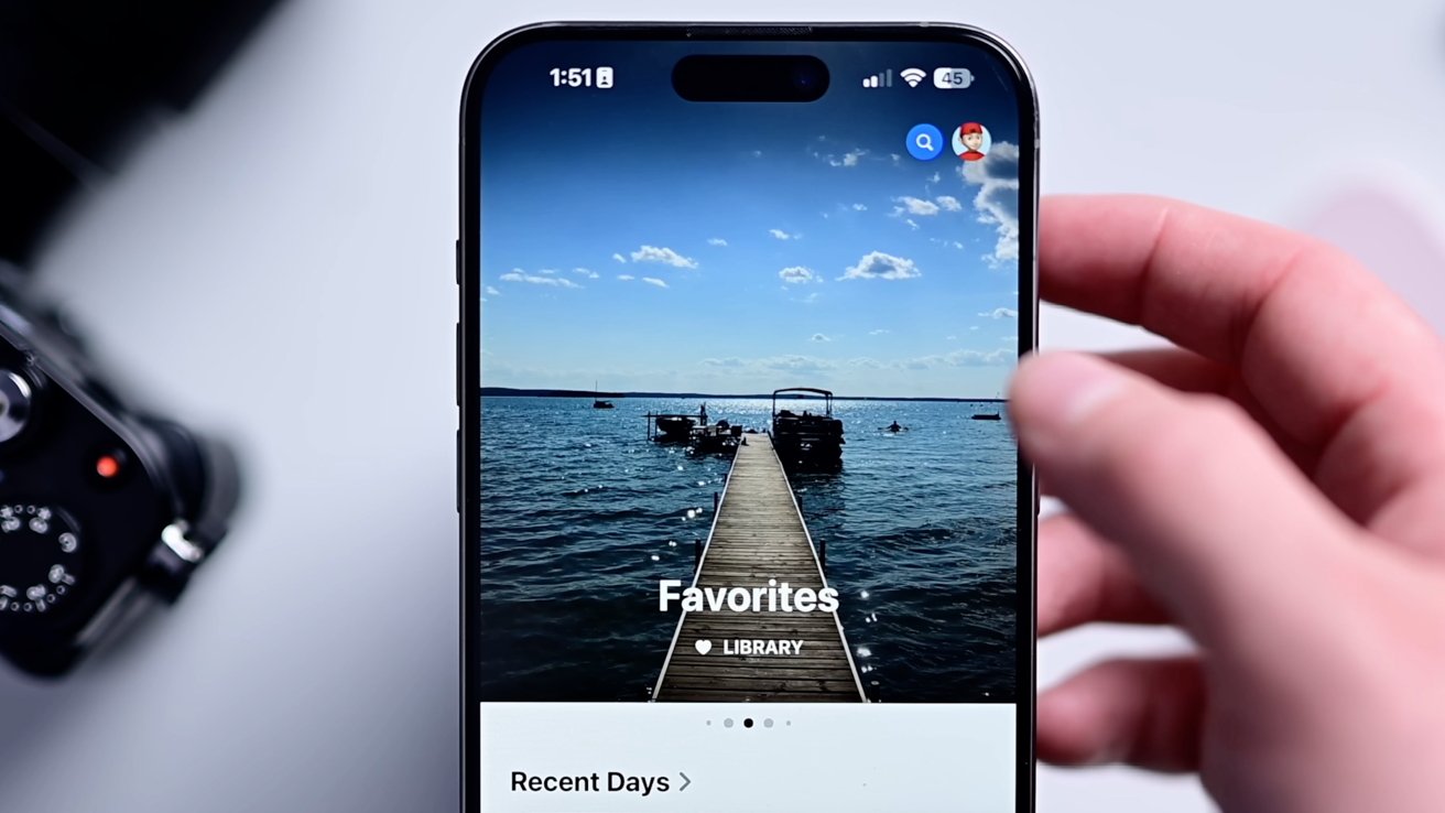 A smartphone screen shows a photo of a dock extending into a lake under a blue sky with scattered clouds.