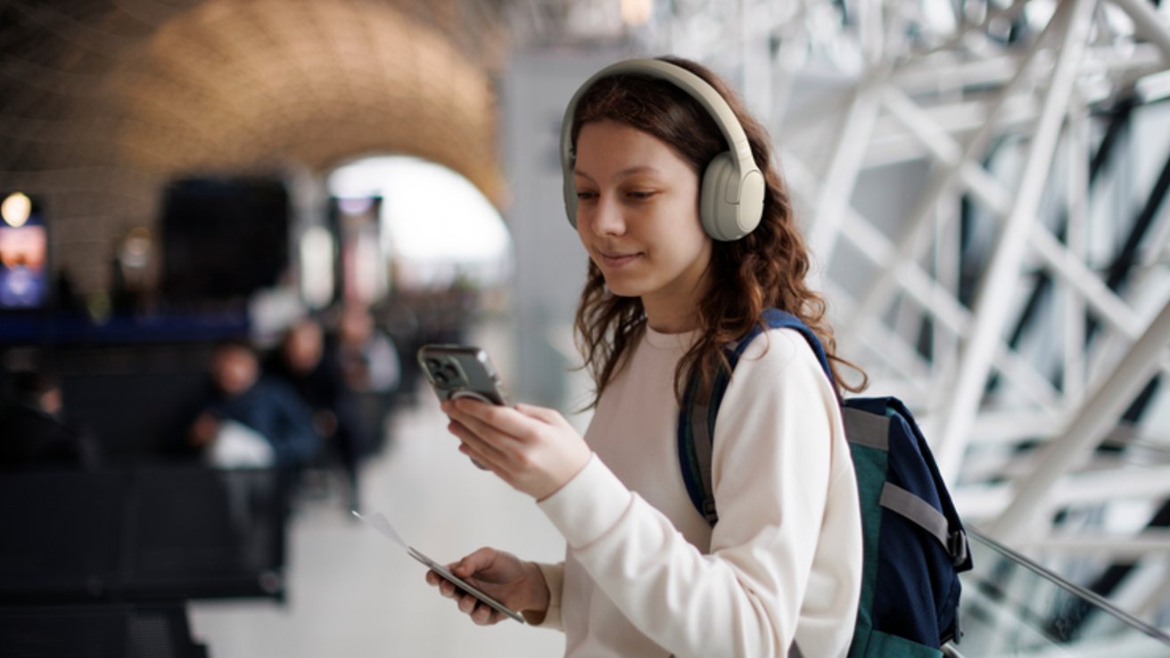 A woman wears on-ear headphones and looks at her phone