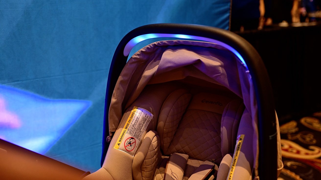 Baby car seat with beige fabric and a glowing blue light overhead, placed against a blue background.