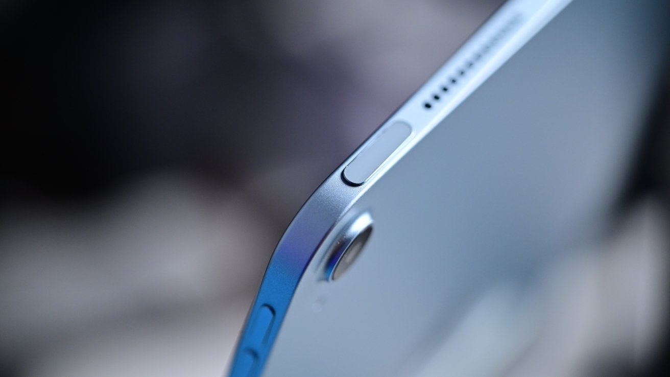 Close-up of a silver tablet corner featuring a camera lens, buttons, and sleek curved edge.