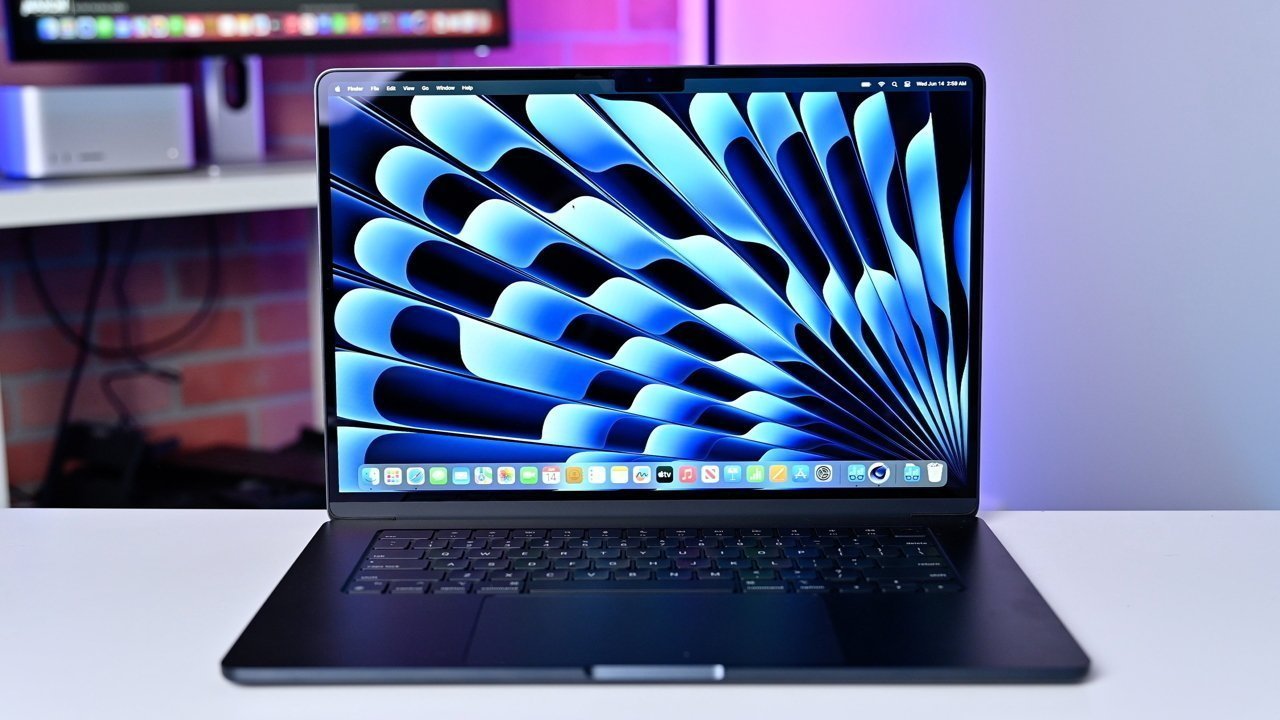 Open laptop on a desk showing a blue abstract design on the screen, set against a softly lit background.