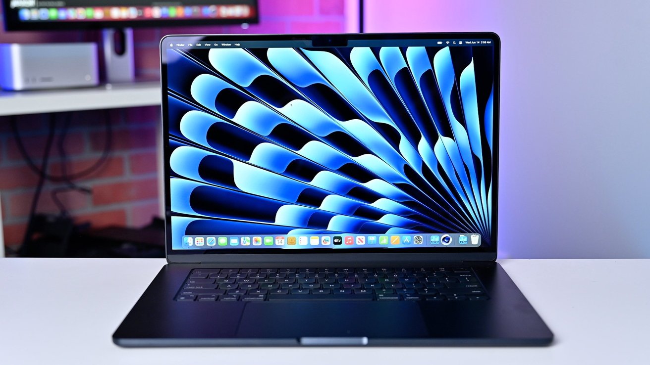 MacBook Air on a white table displaying abstract blue and black spiral pattern on screen, with a blurred background.