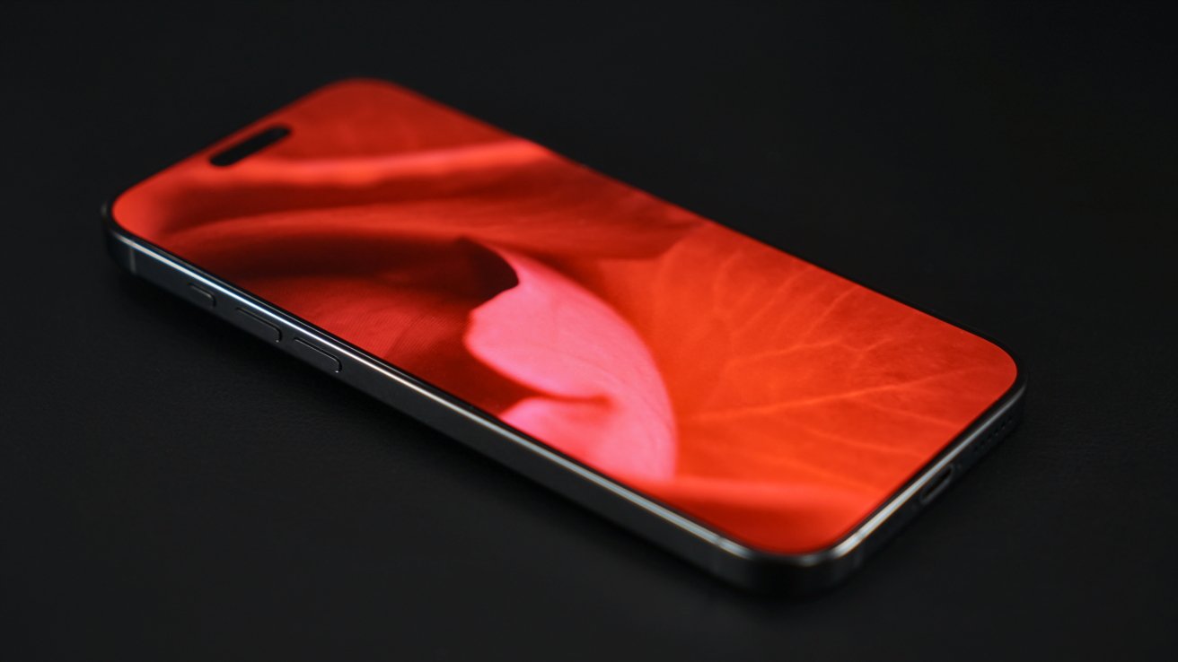 Smartphone with a prominent red floral design on the screen, placed on a black surface.