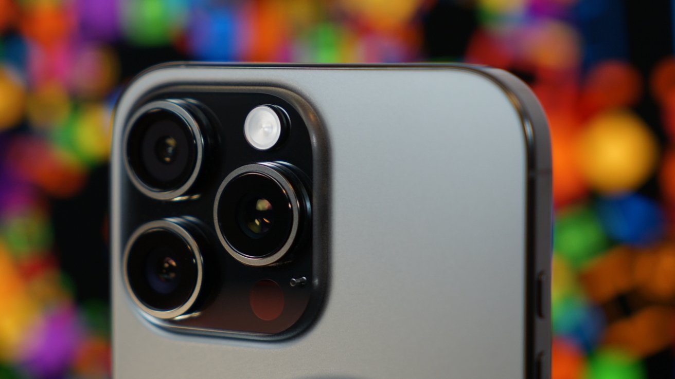 Close-up of an iPhone 16 Pro Max triple-lens camera with a colorful, blurred background.