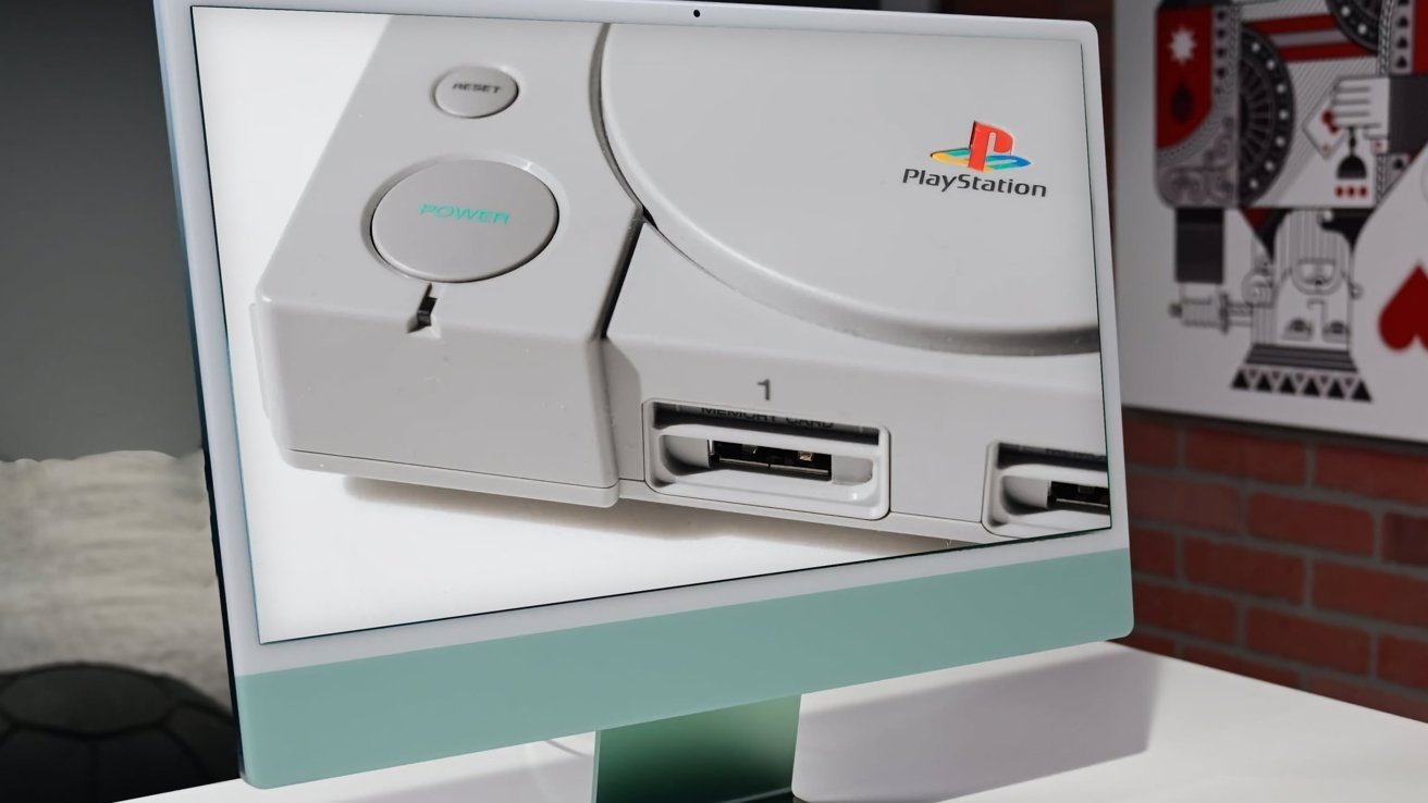 Close-up of a PlayStation console displayed on a screen against a modern setting with a brick wall and artwork in the background.