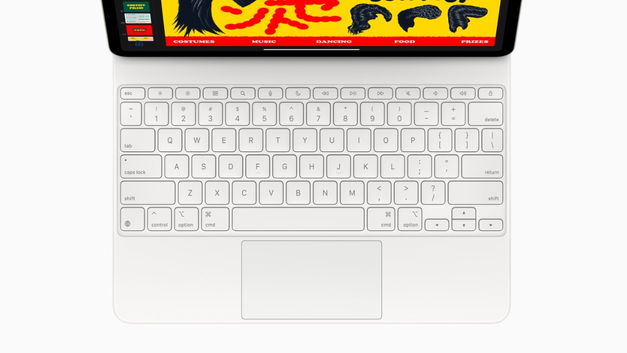 White keyboard with a large touchpad, beneath a screen displaying a bright, colorful graphic featuring a silhouette and text related to costumes, music, dancing, food, and prizes.