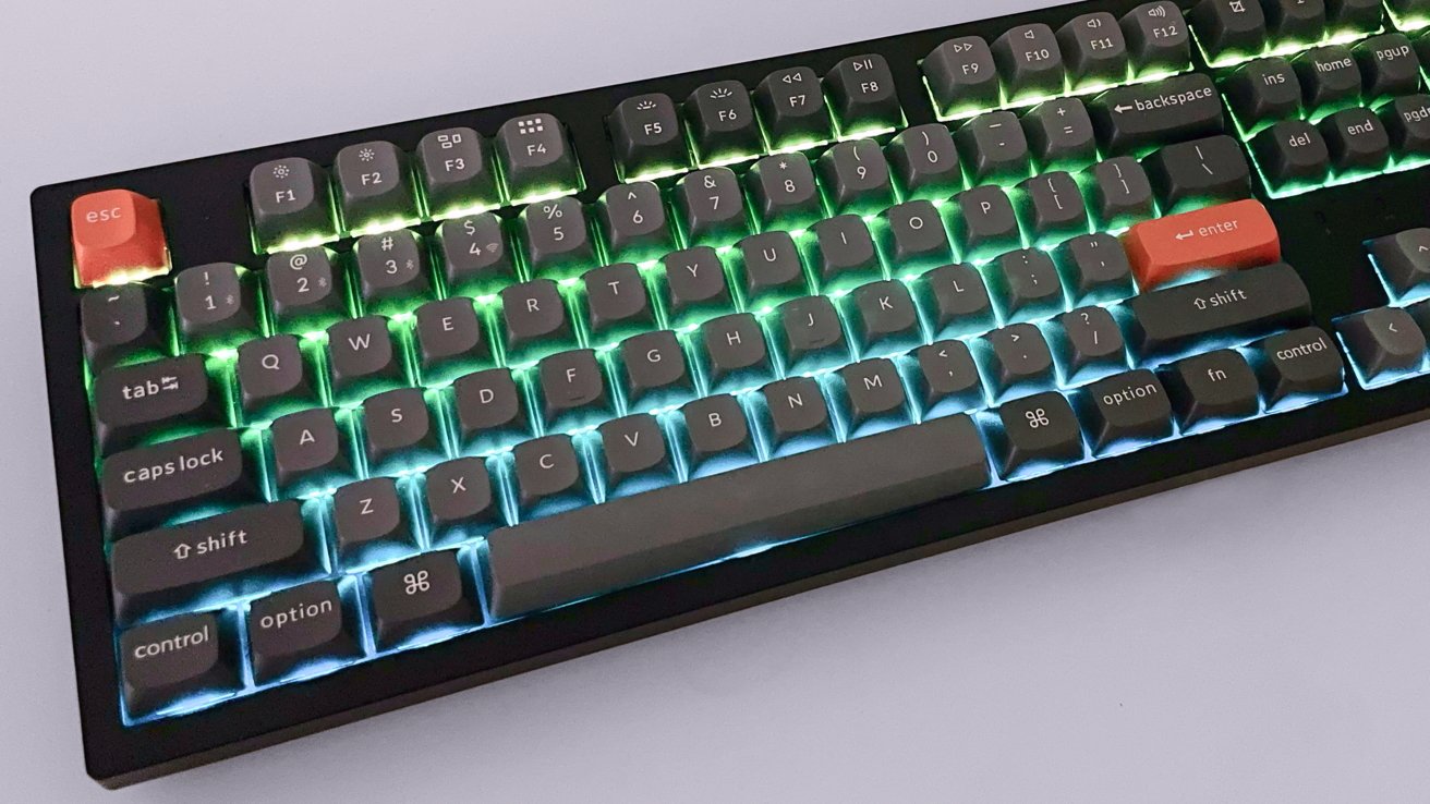 Backlit mechanical keyboard with colorful ambient lighting, featuring distinctive orange escape and enter keys.